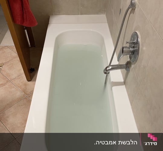 אמבטיה מלאה במים עם ברז ומקלחת יד